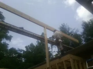 Carpenter setting a ridge beam over a new addition frame — Ice Dam Removal by Roofing Brothers in Emden