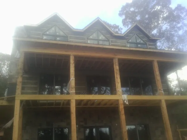 Dormers and porch framing on a large log home under construction — Roof Coating work by our crew in Emden