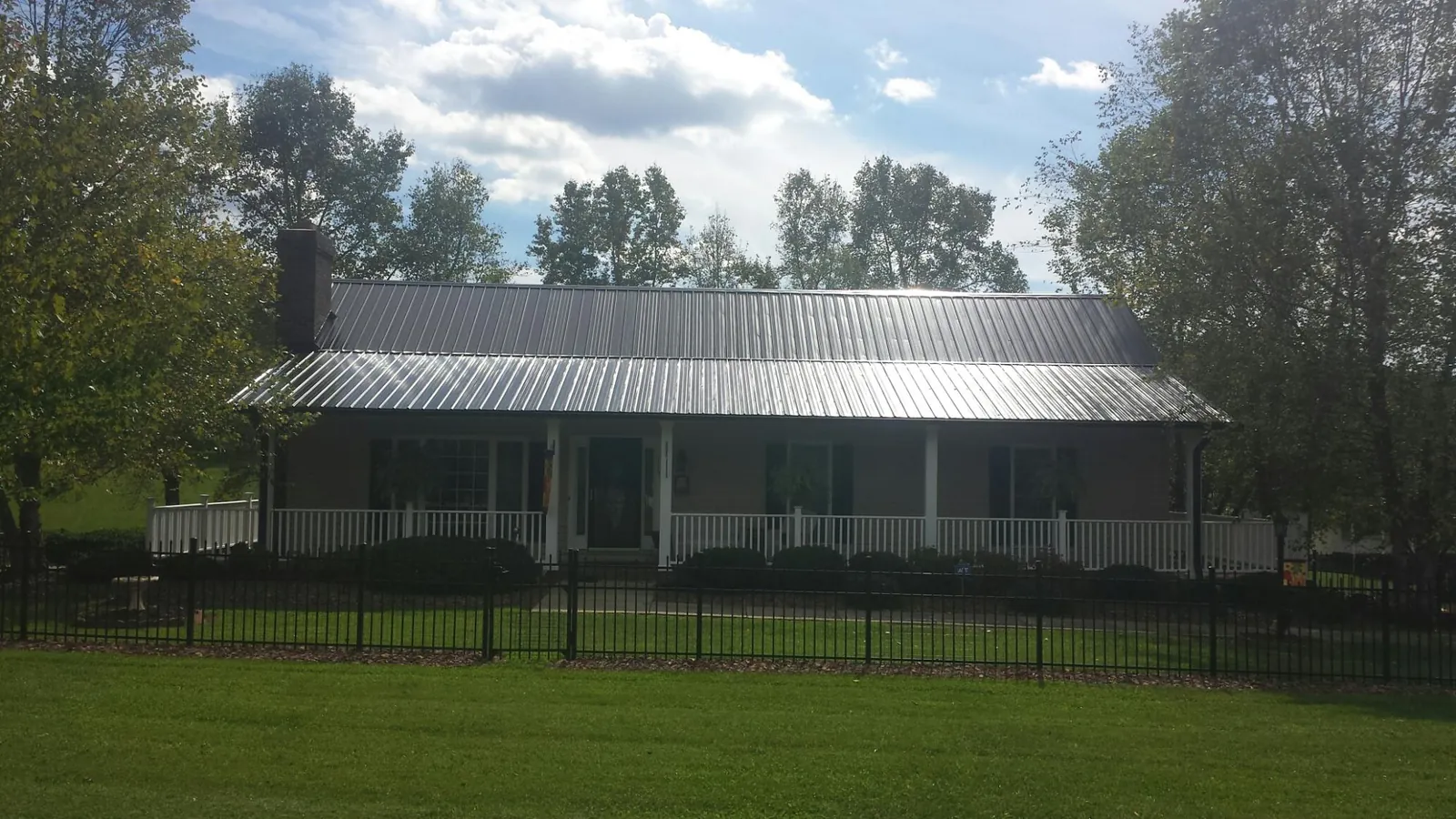 Gray metal roof on a brick ranch with a full width front porch — Gutter Guard Installation work by our crew in Emden