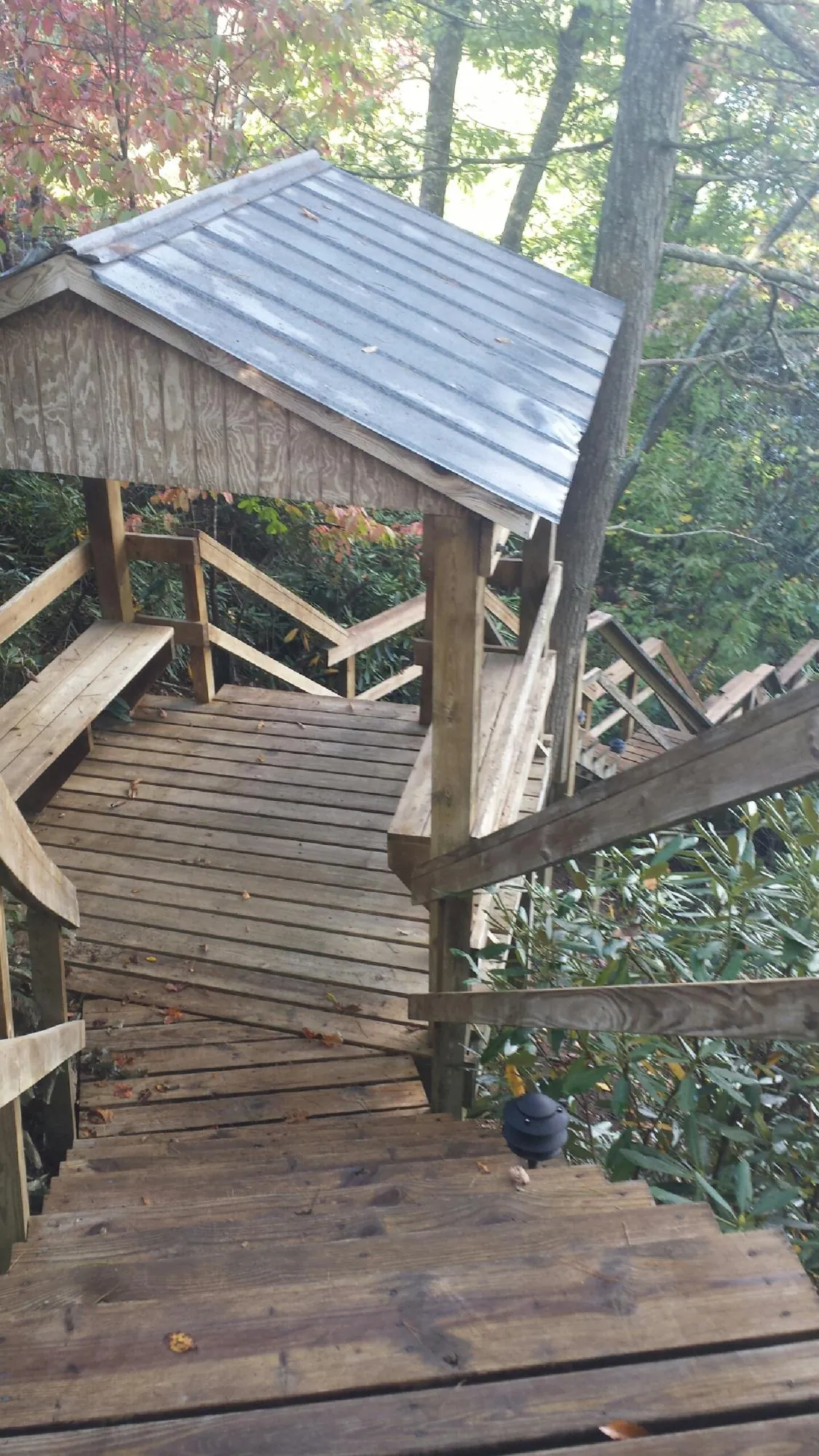 Metal roofed shelter over wooden steps on a wooded walkway — Skylight Repair & Installation work by our crew in Emden